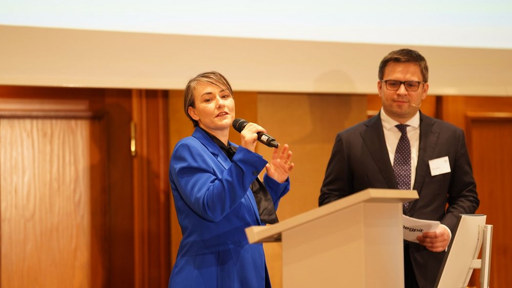 Konferenzmanagerin Mareike Gerhold und Tagungsleiter Dr. Jacob Wende eröffnen gemeinsam den Programmpunkt zur EU-Geldwäscheregulierung